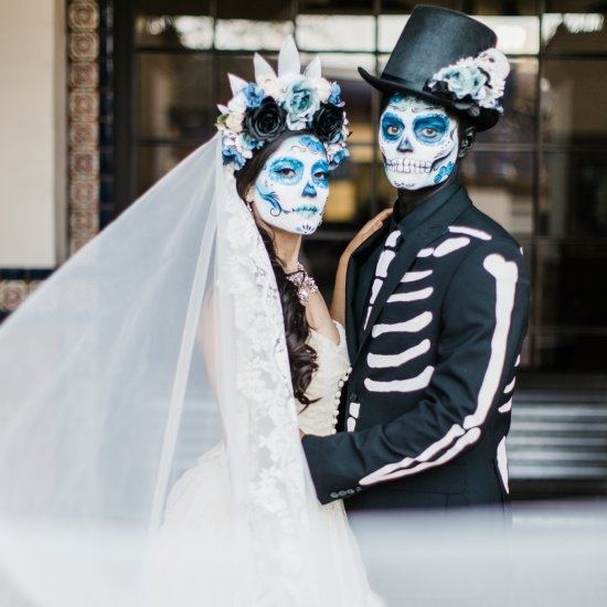 Couple dressed as bride and groom wearing face paint for Dia de Los Muertos/Day of the Dead celebration