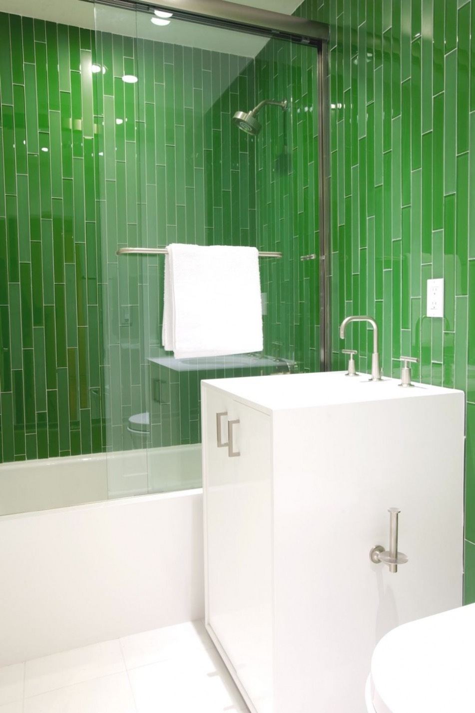 Long, thin green tiles in a vertical pattern around a white bathtub and vanity