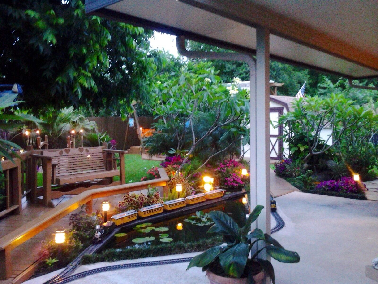 A stone path leads to the front door and passes by a risen pond that sits above the garage